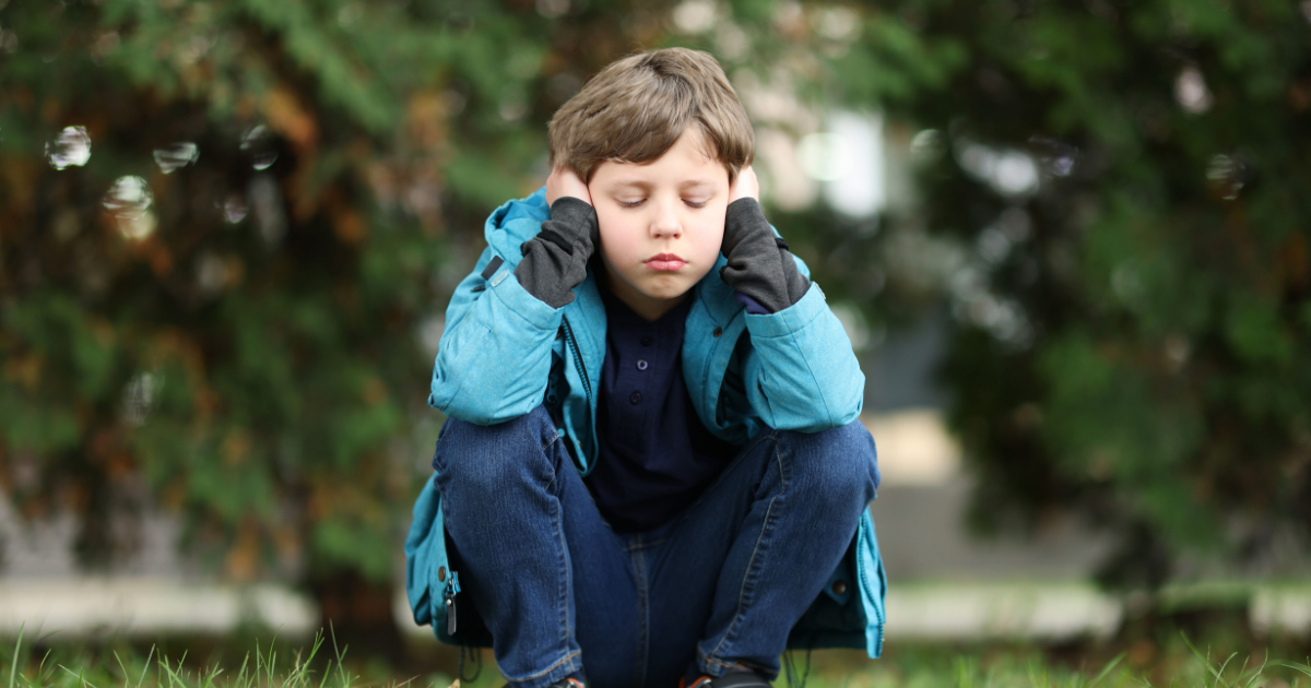 Enfant se bouchant les oreilles à cause d'une surcharge sensorielle, illustrant les conséquences des troubles de l'autisme.