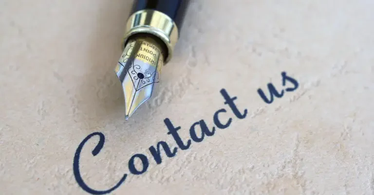 alt="Stylo plume écrivant Contact us sur une carte de contact pour mamans entrepreneures"