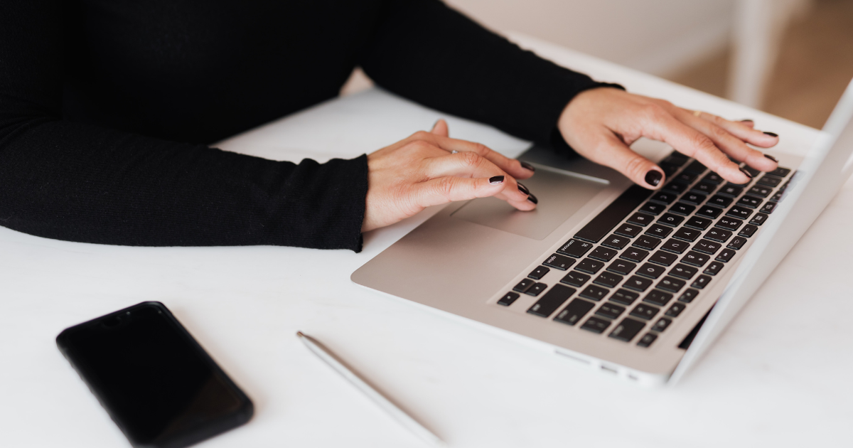 Femme entrepreneure travaillant sur son ordinateur sans montrer son visage, créant une vidéo faceless.