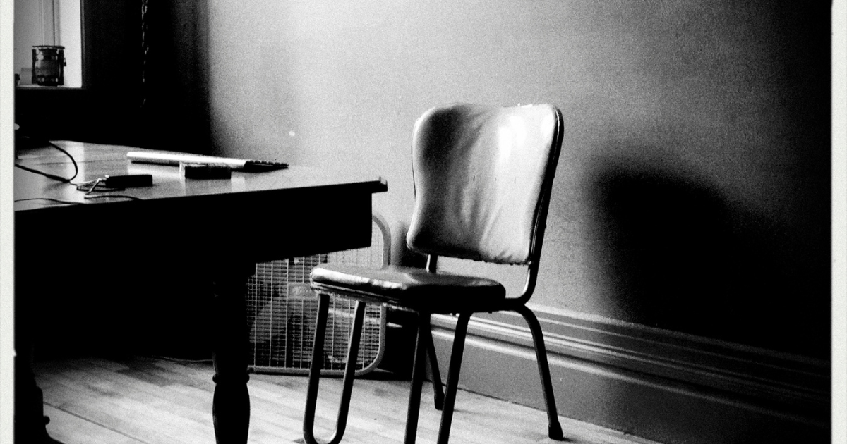 Apprentissage et solitude, chaise vide devant un bureau de travail en noir et blanc.