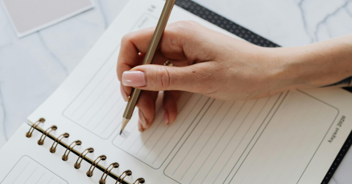Écrire pour entreprendre : une maman rédige dans son carnet, symbole de résilience et de clarté